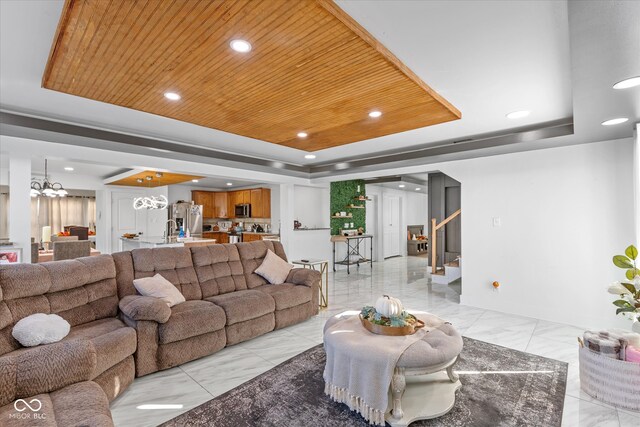 living room with a notable chandelier, wooden ceiling, and a tray ceiling