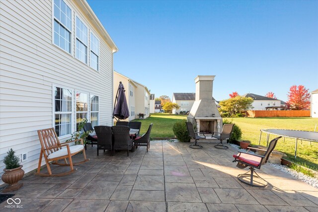 view of patio with a trampoline and an outdoor fireplace