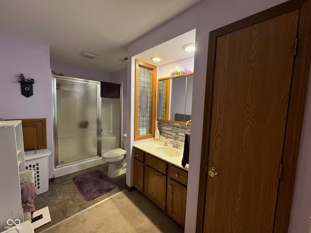 bathroom featuring a shower with door, vanity, toilet, and backsplash