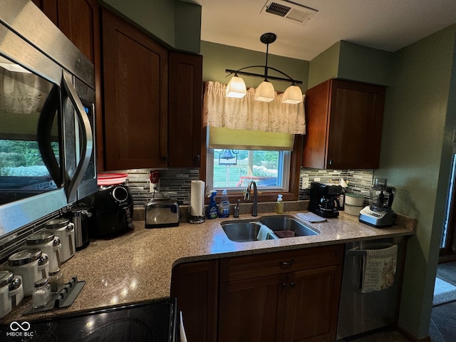 kitchen featuring tasteful backsplash, hanging light fixtures, sink, and stainless steel appliances