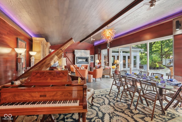 miscellaneous room featuring french doors, ceiling fan with notable chandelier, a fireplace, and wood walls