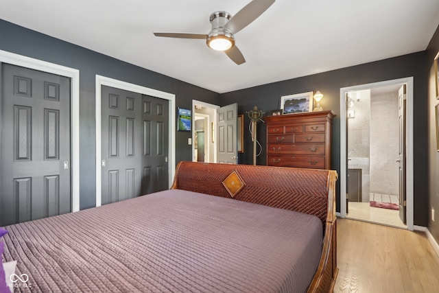 bedroom with ceiling fan, light hardwood / wood-style flooring, connected bathroom, and two closets