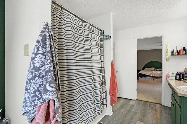 bathroom with vanity, wood-type flooring, a textured ceiling, and walk in shower