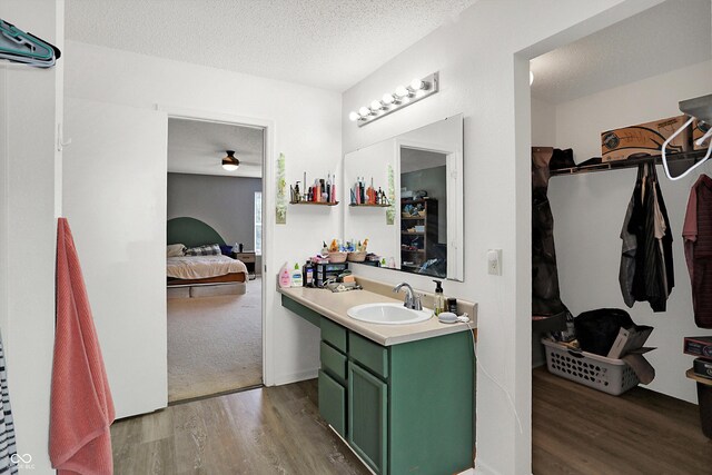 bathroom with hardwood / wood-style floors, ceiling fan, a textured ceiling, and vanity