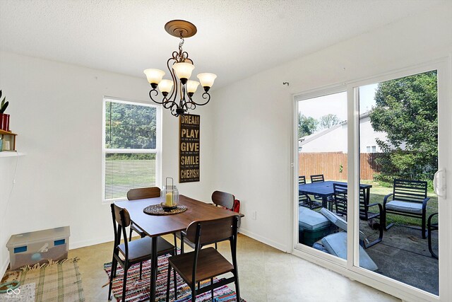 dining space featuring plenty of natural light, a textured ceiling, and an inviting chandelier