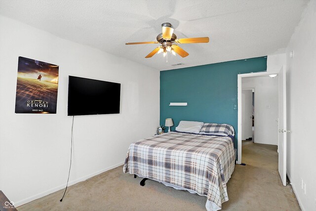 carpeted bedroom featuring ceiling fan and a textured ceiling