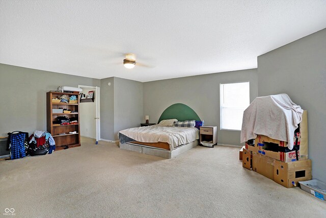 carpeted bedroom featuring ceiling fan and a textured ceiling