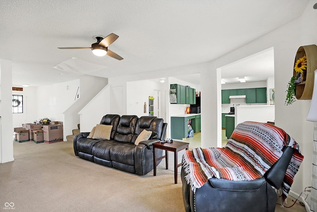 living room featuring ceiling fan, a textured ceiling, and light carpet