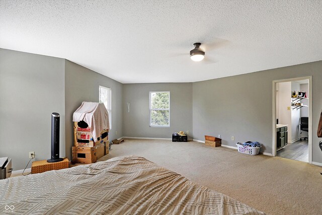 carpeted bedroom with ceiling fan, a walk in closet, and a textured ceiling