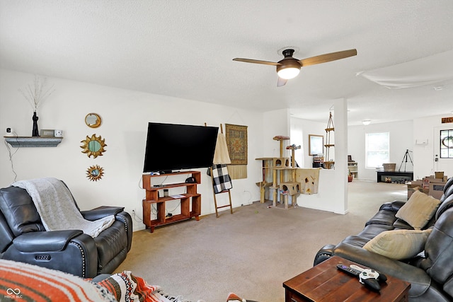 carpeted living room with ceiling fan and a textured ceiling