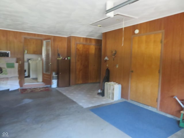 garage with washing machine and clothes dryer, radiator, and wood walls