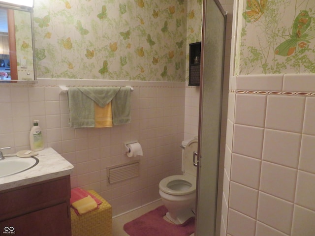 full bath featuring wallpapered walls, toilet, vanity, a stall shower, and wainscoting