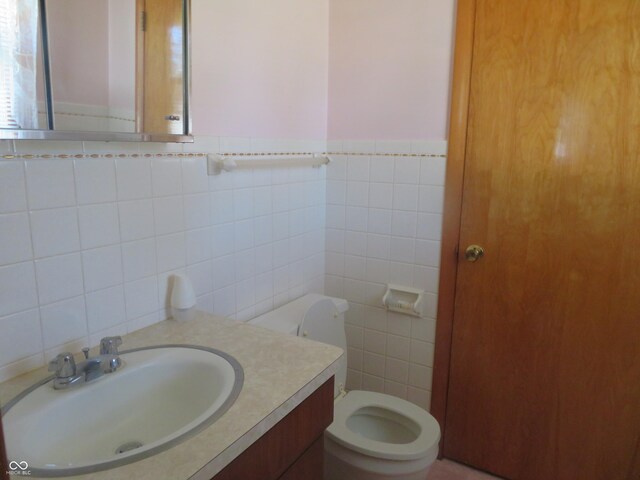 half bath featuring tile walls, toilet, and vanity