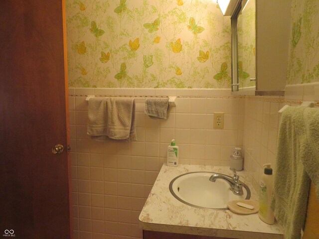 bathroom with wallpapered walls, vanity, and wainscoting