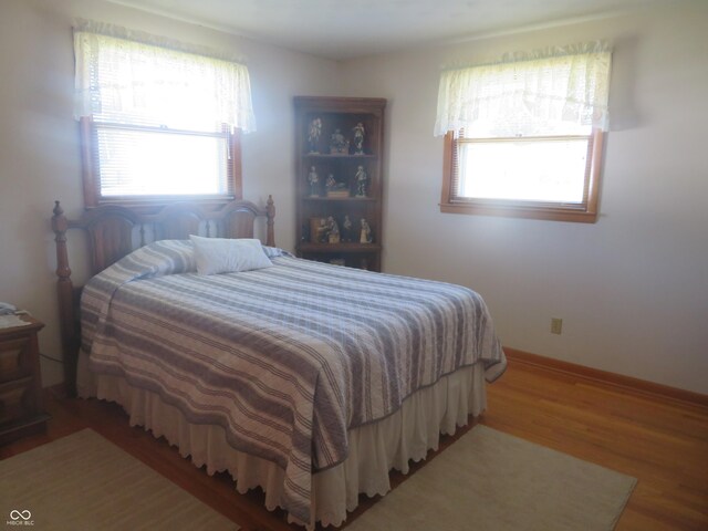 bedroom with multiple windows and wood finished floors