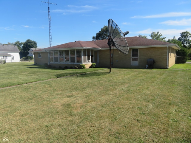 rear view of property with a sunroom and a lawn