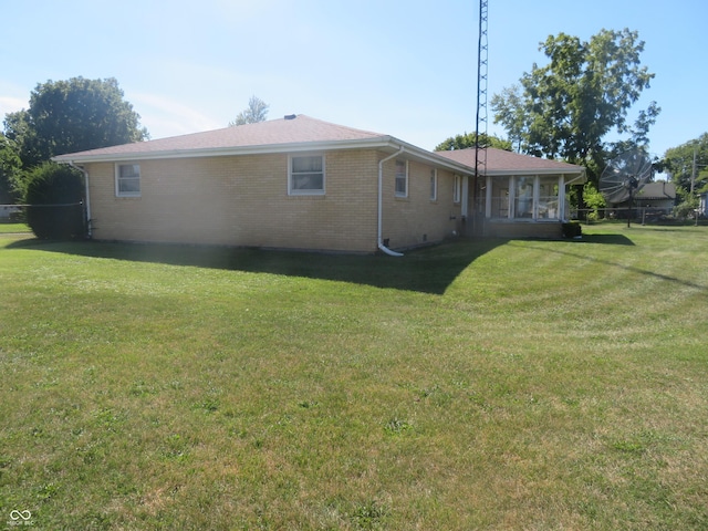 rear view of house with a lawn, fence, and brick siding