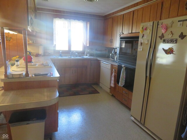 kitchen featuring light countertops, a sink, a peninsula, white appliances, and decorative backsplash