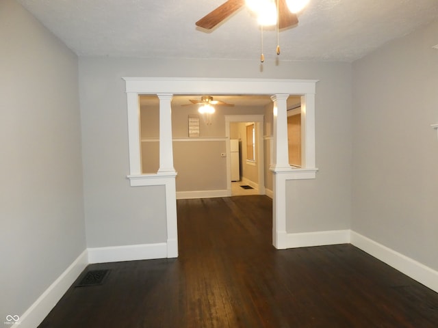 empty room featuring decorative columns, ceiling fan, and dark hardwood / wood-style flooring