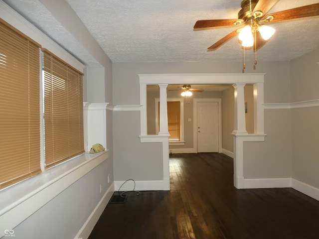 spare room featuring a textured ceiling, ceiling fan, dark hardwood / wood-style floors, and decorative columns