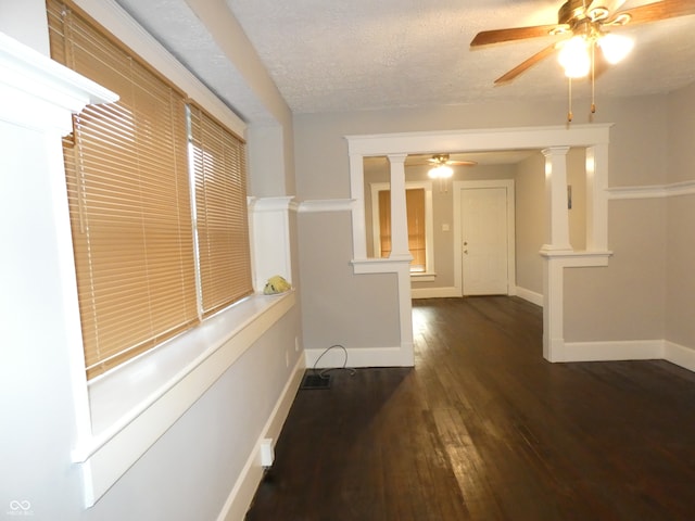 hall featuring a textured ceiling, dark wood-type flooring, and ornate columns