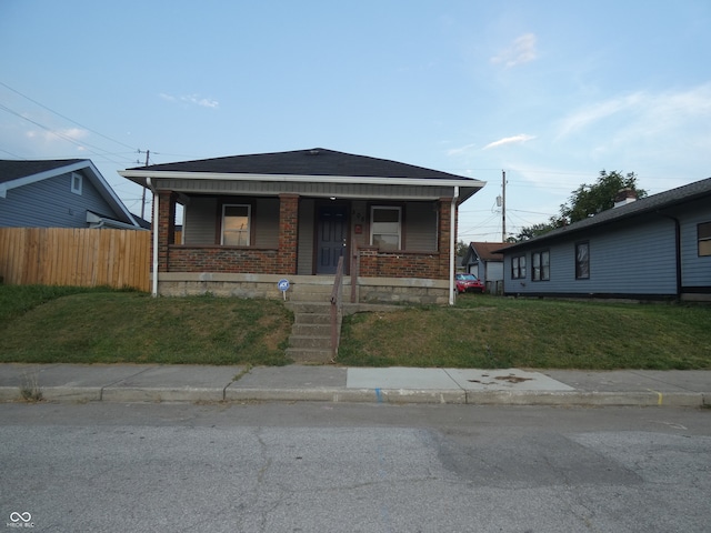 bungalow-style home with a front yard and covered porch