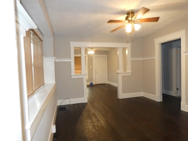 unfurnished room featuring decorative columns, ceiling fan, dark hardwood / wood-style flooring, and a textured ceiling