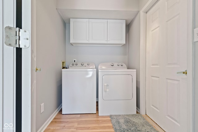 laundry room featuring light hardwood / wood-style flooring, washing machine and clothes dryer, and cabinets