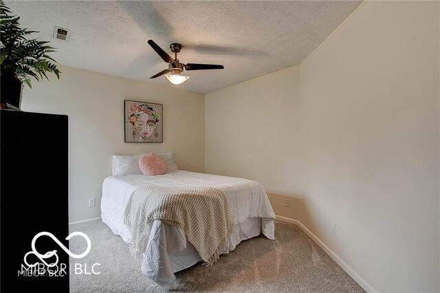 carpeted bedroom featuring a textured ceiling and ceiling fan