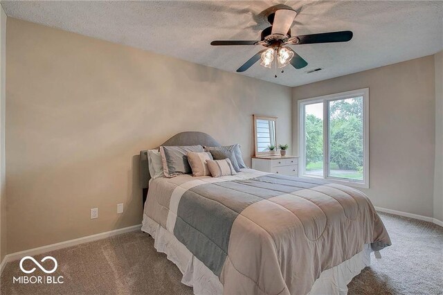 bedroom with ceiling fan, light carpet, and a textured ceiling