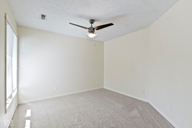 carpeted spare room with ceiling fan, a healthy amount of sunlight, and a textured ceiling