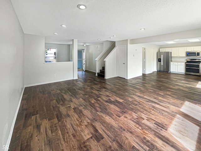 unfurnished living room featuring dark wood-type flooring and a textured ceiling