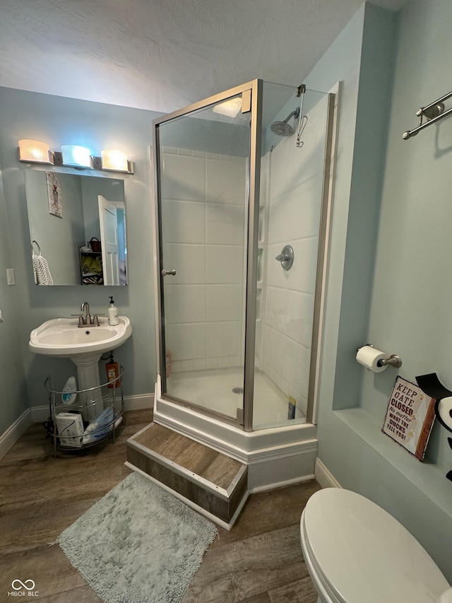 bathroom with toilet, hardwood / wood-style floors, sink, and a shower with door