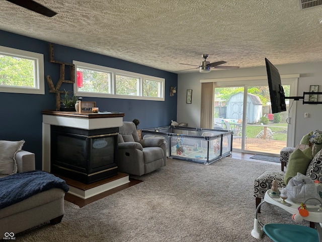 carpeted living room with a textured ceiling, ceiling fan, and a multi sided fireplace