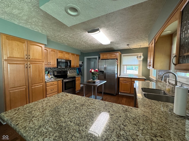 kitchen featuring a textured ceiling, dark hardwood / wood-style flooring, stainless steel appliances, sink, and kitchen peninsula