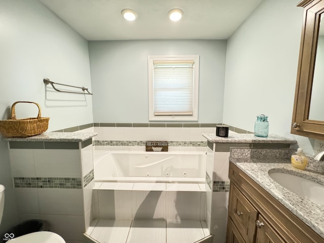 bathroom with tiled bath, toilet, and vanity