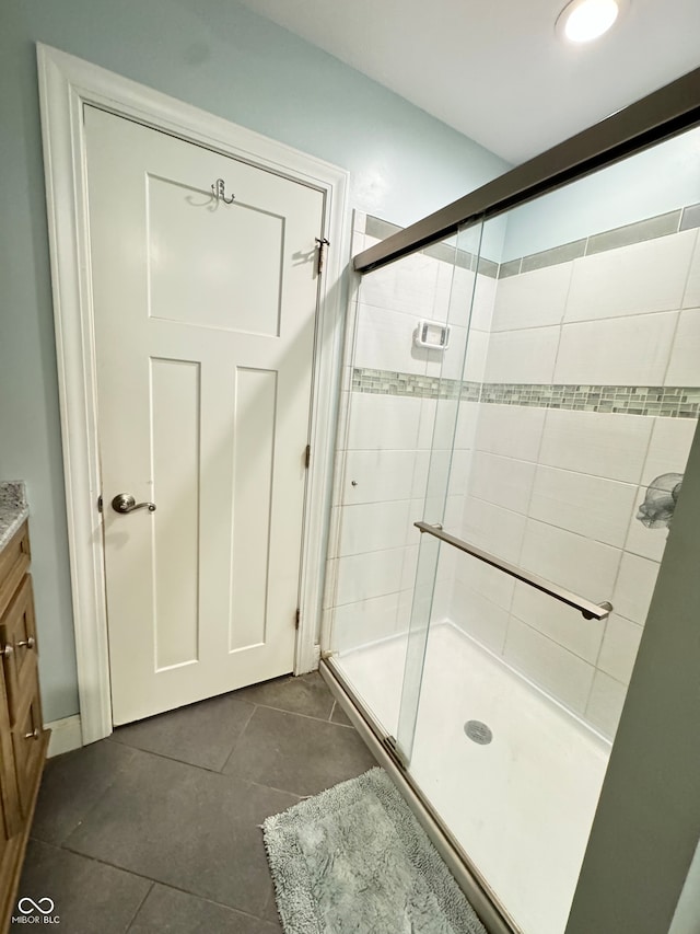 bathroom featuring tile patterned flooring, a shower with door, and vanity