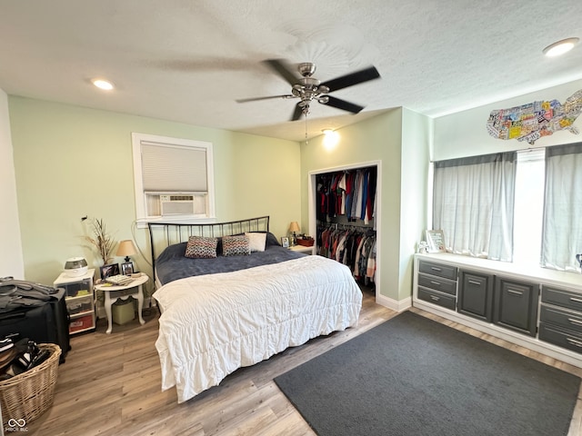 bedroom featuring cooling unit, a closet, dark wood-type flooring, ceiling fan, and a textured ceiling