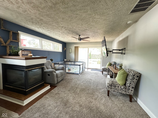 interior space with a textured ceiling, carpet, ceiling fan, and a multi sided fireplace