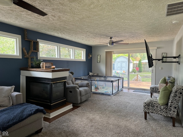 carpeted living room with a textured ceiling, plenty of natural light, and ceiling fan