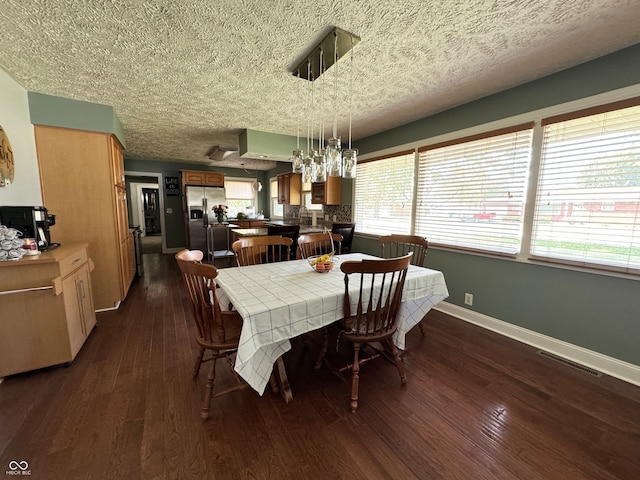 dining room with a textured ceiling, a notable chandelier, and dark hardwood / wood-style flooring