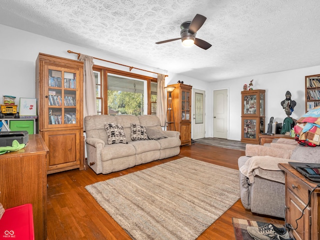 living area with ceiling fan, a textured ceiling, and wood finished floors