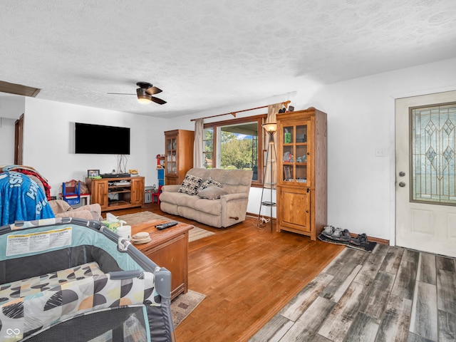 living room with a ceiling fan, wood finished floors, and a textured ceiling