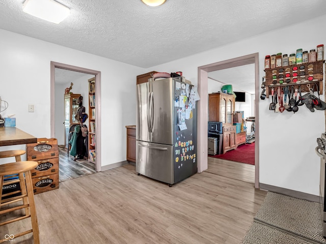 kitchen with light wood-style floors, freestanding refrigerator, and a textured ceiling