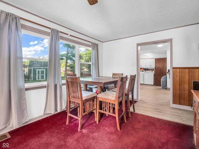 dining area with plenty of natural light, washing machine and dryer, wood walls, and a wainscoted wall