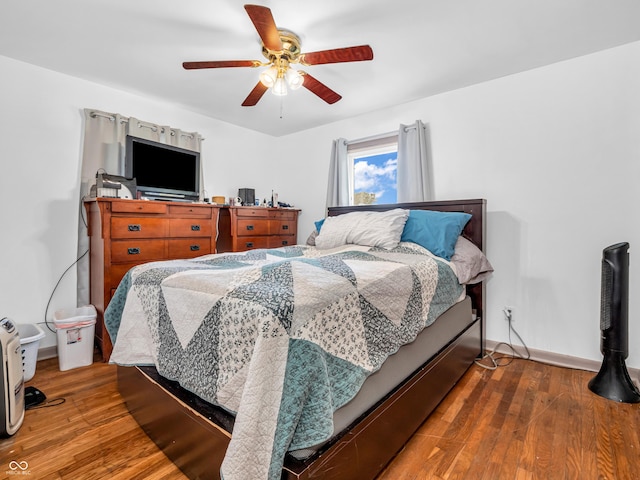 bedroom with a ceiling fan, baseboards, and wood-type flooring