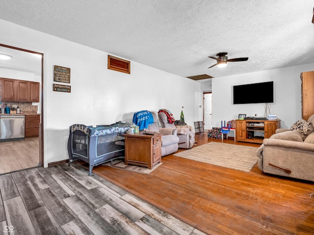 living area featuring a textured ceiling, ceiling fan, and wood finished floors