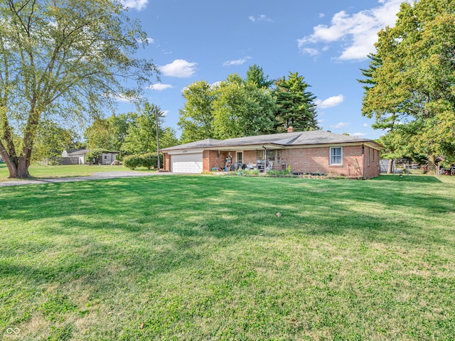 ranch-style home featuring a front lawn, an attached garage, brick siding, and a chimney