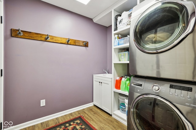 washroom featuring light hardwood / wood-style flooring, cabinets, and stacked washer / dryer