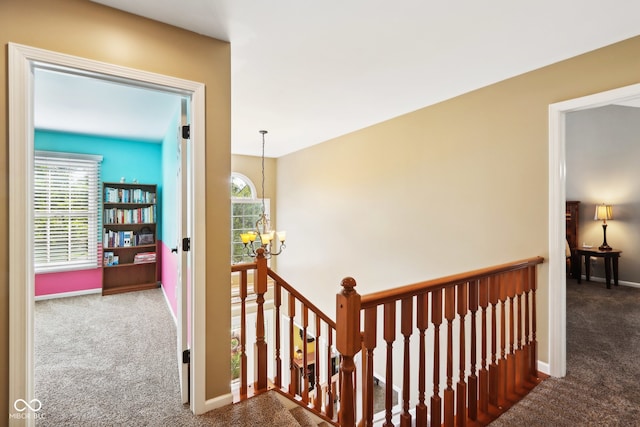 hallway featuring a wealth of natural light, carpet, and a chandelier